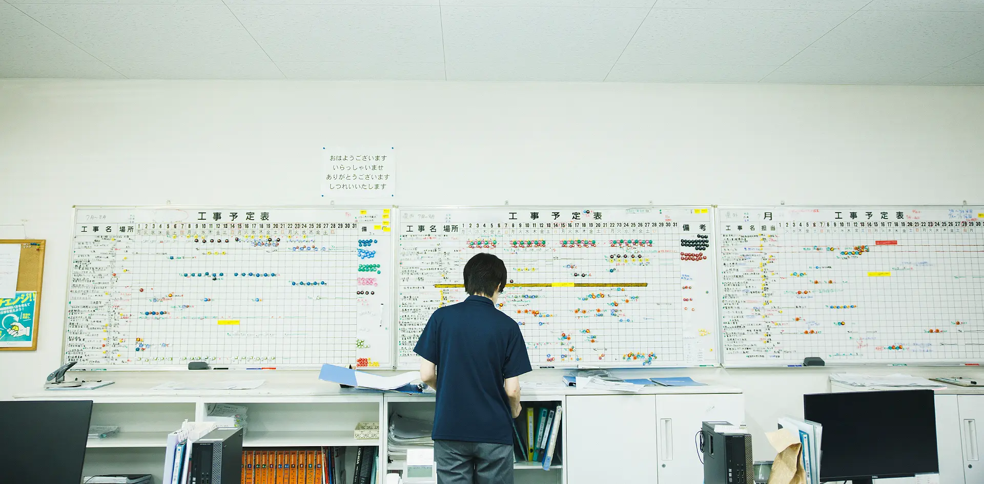 工事予定表の前で作業するスタッフ